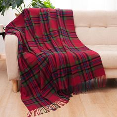 a red plaid blanket sitting on top of a wooden floor next to a white couch