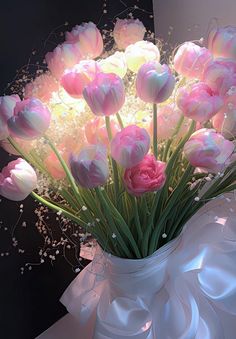 a white vase filled with pink flowers on top of a table