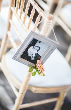 an old photo hanging from a chair with flowers on the seat and a flower in front of it