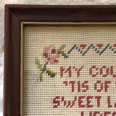 a cross stitch sample in a wooden frame