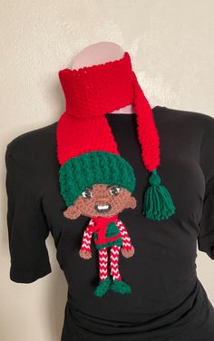 a woman wearing a black shirt with a red and green knitted elf hat on it's head