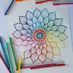 colored pencils and crayons on a paper with a drawing of a flower