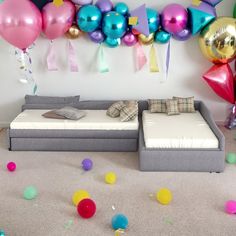 balloons and streamers are scattered around a couch in a room with white carpeting