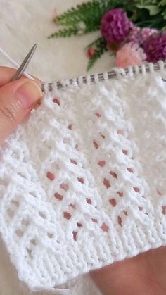 someone is crocheting on the edge of a piece of white fabric with scissors