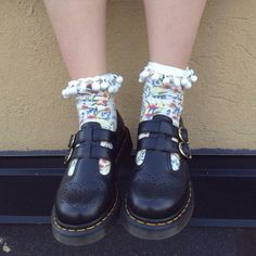 a pair of black shoes with flowers on them and white laces around the ankles