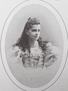 an old black and white photo of a woman with long hair wearing a ruffled blouse