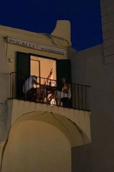 two men are playing on the balcony of an apartment building at night with their instruments