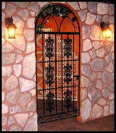 a stone wall with an iron gate and two lights