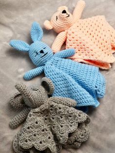 four crocheted stuffed animals laying on top of a bed next to each other