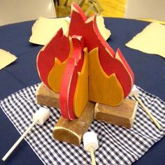 a table topped with a paper fire and marshmallows on top of it