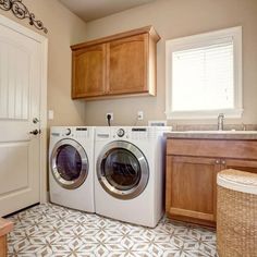 a washer and dryer sitting in a room next to a sink with wooden cabinets