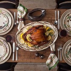 a turkey is sitting on a table with plates and silverware, napkins and forks