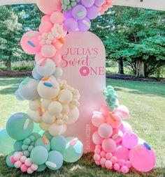 there is a pink and blue balloon arch with balloons all over the top, along with other balloons