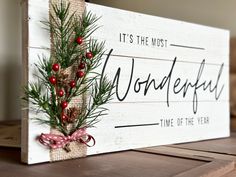 a wooden sign that says it's the most wonderful time of the year with pine branches