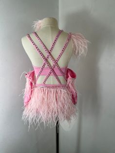 a mannequin with pink feathers and beading on it's chest, standing in front of a white wall