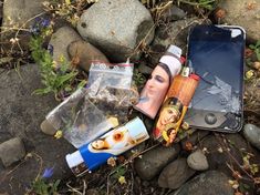 an open cell phone laying on the ground next to some rocks and other items that have been placed around it