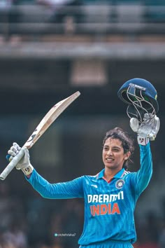 a woman holding a cricket bat in her right hand and wearing a helmet with the word india on it