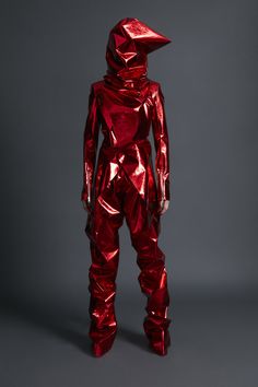 a person in red shiny clothing standing on a gray surface with their back turned to the camera