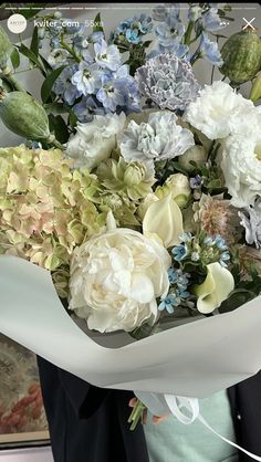 a woman holding a bouquet of white and blue flowers