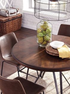 a wooden table with chairs around it and a vase full of fruit on the table