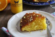 a piece of cake on a plate with a fork and orange juice in the background