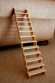 there is a small wooden staircase going up the carpeted floor next to a couch