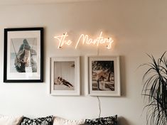 three framed photographs hang on the wall next to a couch with two pillows and a potted plant