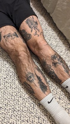 a man laying on the floor with his legs covered in tattoos and socks over his feet