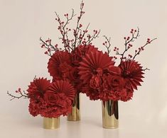 three gold vases with red flowers in them