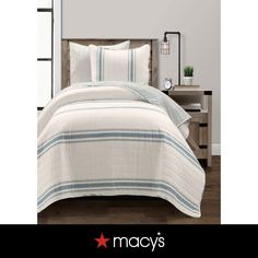 a bed with white and blue striped comforter in a bedroom next to a night stand