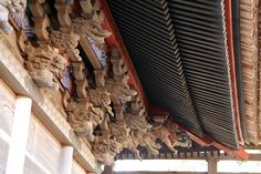 the roof of a building with intricate carvings on it's sides and wood slats