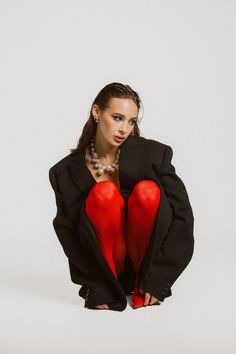 a woman in red stockings and black jacket sitting on the ground