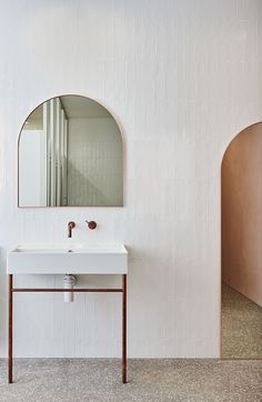 a white sink sitting under a mirror next to a wall mounted faucet in a bathroom