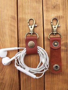 an earphone and headphones hanging on a wooden wall next to a pair of leather keychains