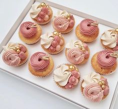 twelve cupcakes with pink icing and white frosting in a gift box