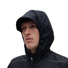 a man wearing a black jacket and hoodie looking off to the side with his head tilted