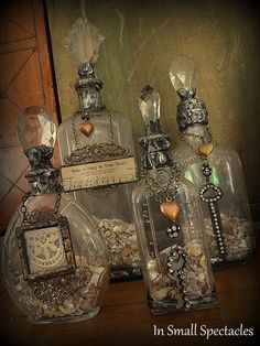 three glass bottles filled with jewelry sitting on top of a table