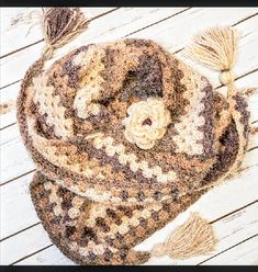 a brown and white scarf with tassels laying on top of a wooden floor