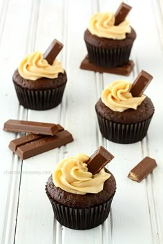 chocolate cupcakes with peanut butter frosting and chocolate bars on white wood background