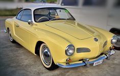 an old yellow sports car parked in a parking lot