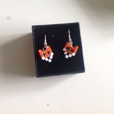 small orange and white beaded earrings sitting on top of a black box