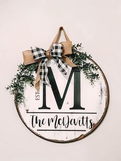 a wooden sign with the letter m hanging from it's side, decorated with greenery