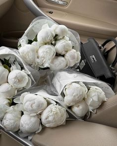 bouquets of white flowers sitting in the back seat of a car, next to a purse