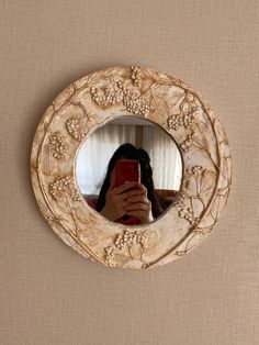 a woman taking a selfie with her cell phone in front of a round mirror