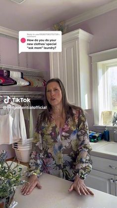 a woman sitting at a kitchen counter in front of a shelf with shirts on it