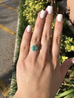 a woman's hand with a ring on it and a green stone in the middle