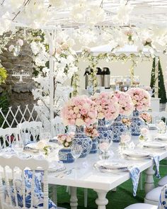 the table is set with blue and white china vases, flowers, and plates