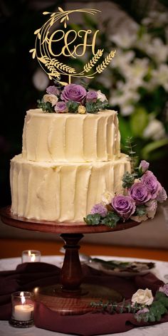 a wedding cake with purple flowers and greenery