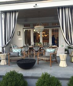 an outdoor patio with chairs and tables in front of a building that has black and white striped drapes on the windows