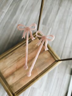 two pink lollipop sticks tied to a wooden tray